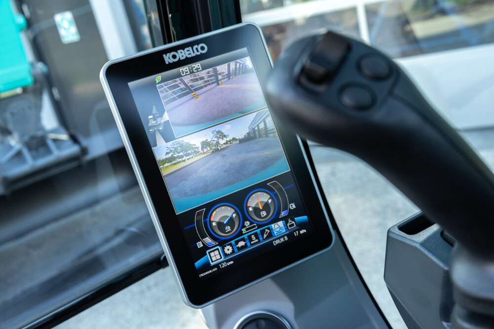 Bedieningsscherm Kobelco SK130 met camerabeelden, uitrustingsstukken selecteren en meer